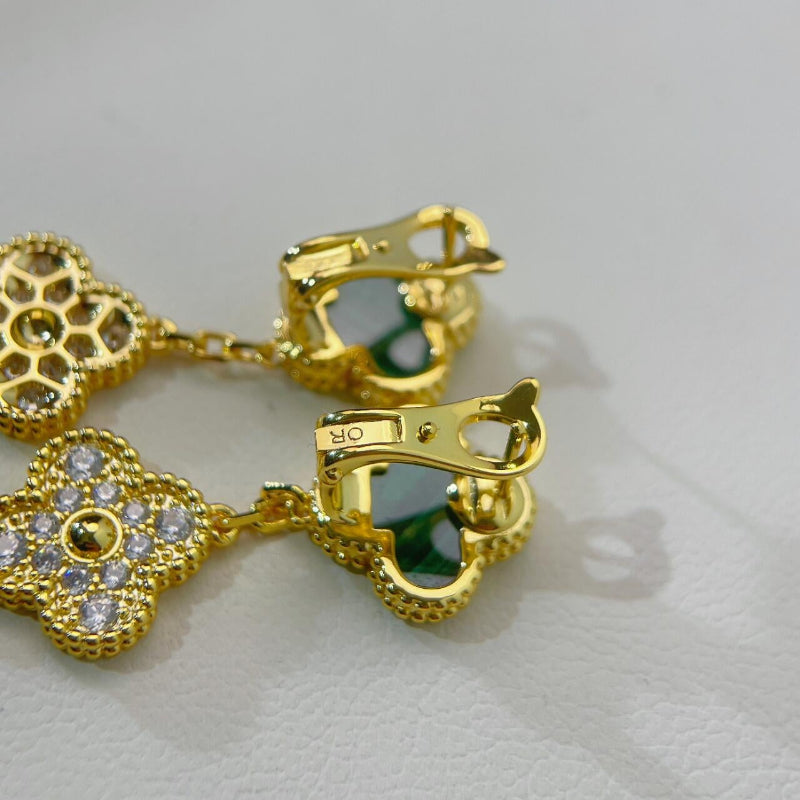 close up of three different sized clover motifs with malachite and crystal pave on yellow gold earrings