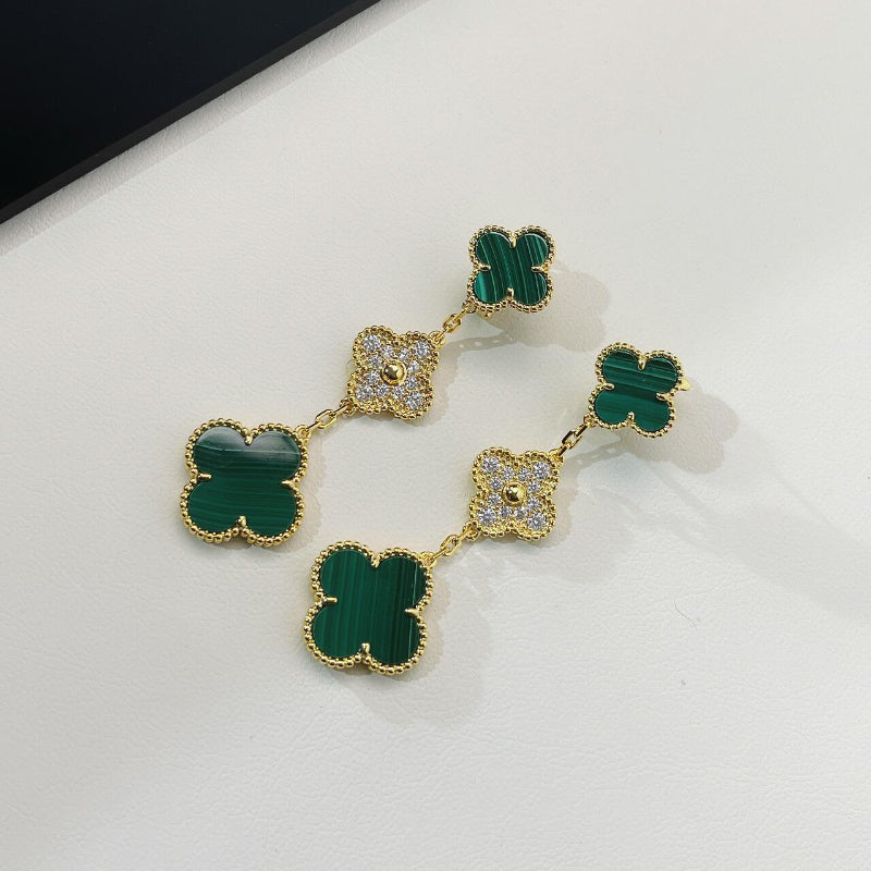 close up of three different sized clover motifs with malachite and crystal pave on yellow gold earrings