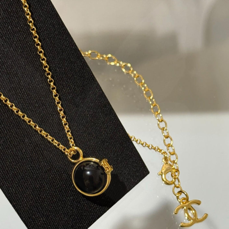 close up of CC black onyx and white pearl bead ball pendant on 18K gold chain