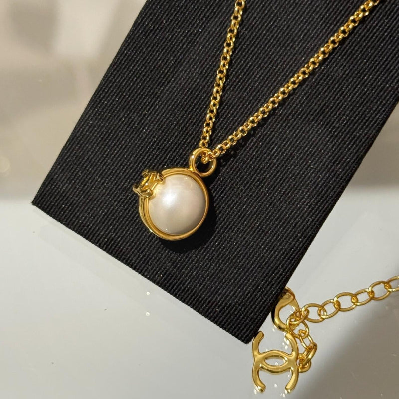 close up of CC black onyx and white pearl bead ball pendant on 18K gold chain
