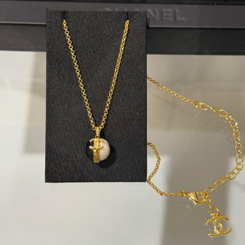 close up of CC black onyx and white pearl bead ball pendant on 18K gold chain