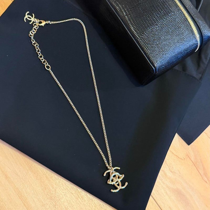 close up of interlocking CC logo pendant necklace gold tone