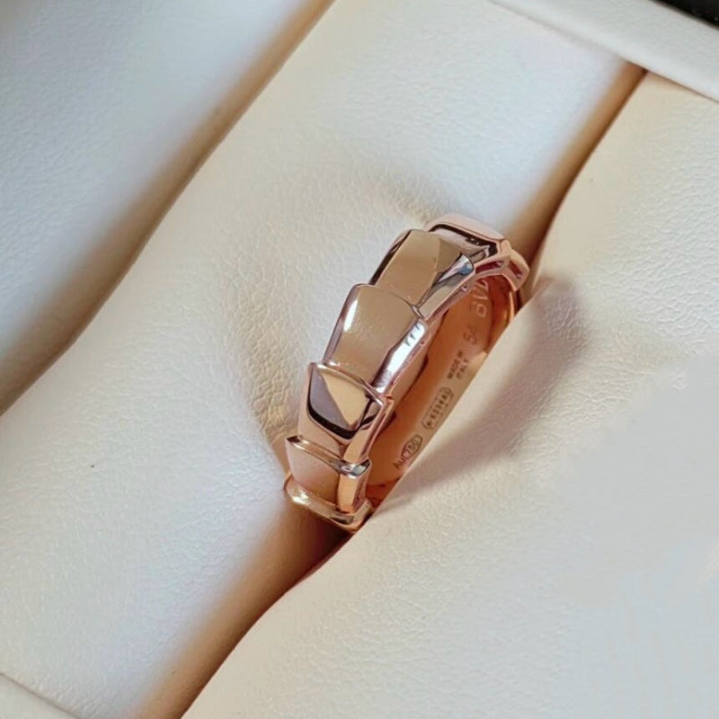 Serpenti Viper style 18K gold wide band ring on white background