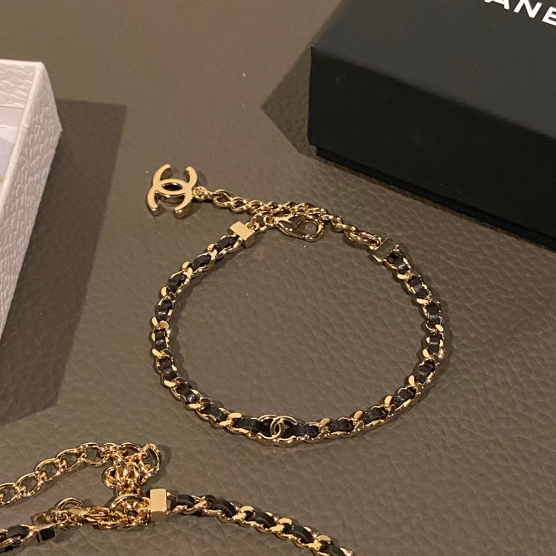 close up of CC black leather interwoven through gold chain link bracelet 18K plated